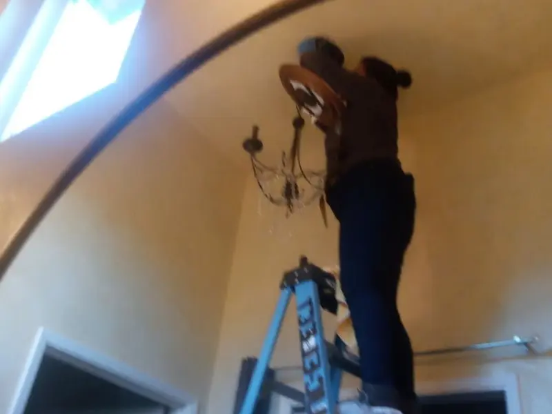 Electrician installing a chandelier in a Springdale residence